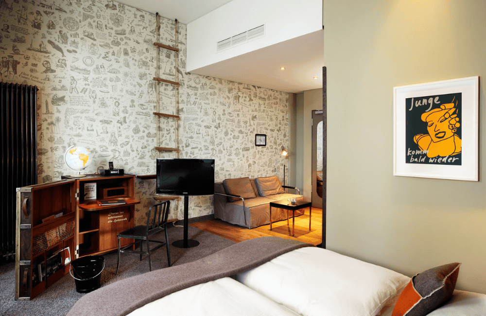 Hotel room featuring a unique graphic wall, modern furnishings, a cosy seating area, and a desk with a globe.