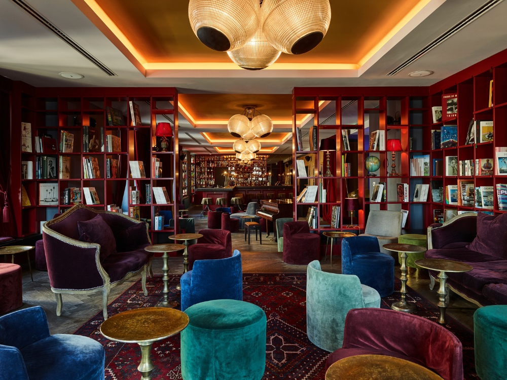 Library mit roten Bücherregalen, Samtsesseln und Bar im Hintergrund