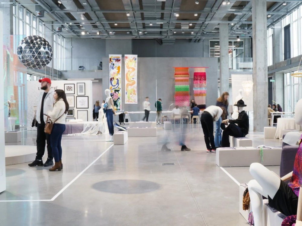 A modern art gallery with colorful displays and visitors exploring various artworks, featuring abstract art and stylish mannequins.