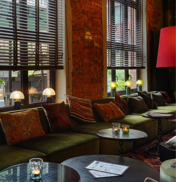 A cozy bar lounge with patterned cushions and round tables.