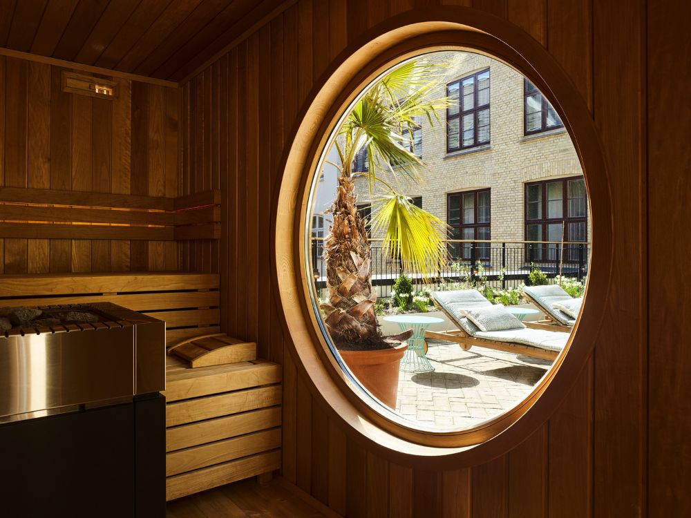A cosy sauna room at 25hours Hotel Indre By, with soft lighting and wooden benches creating a warm, relaxing atmosphere.