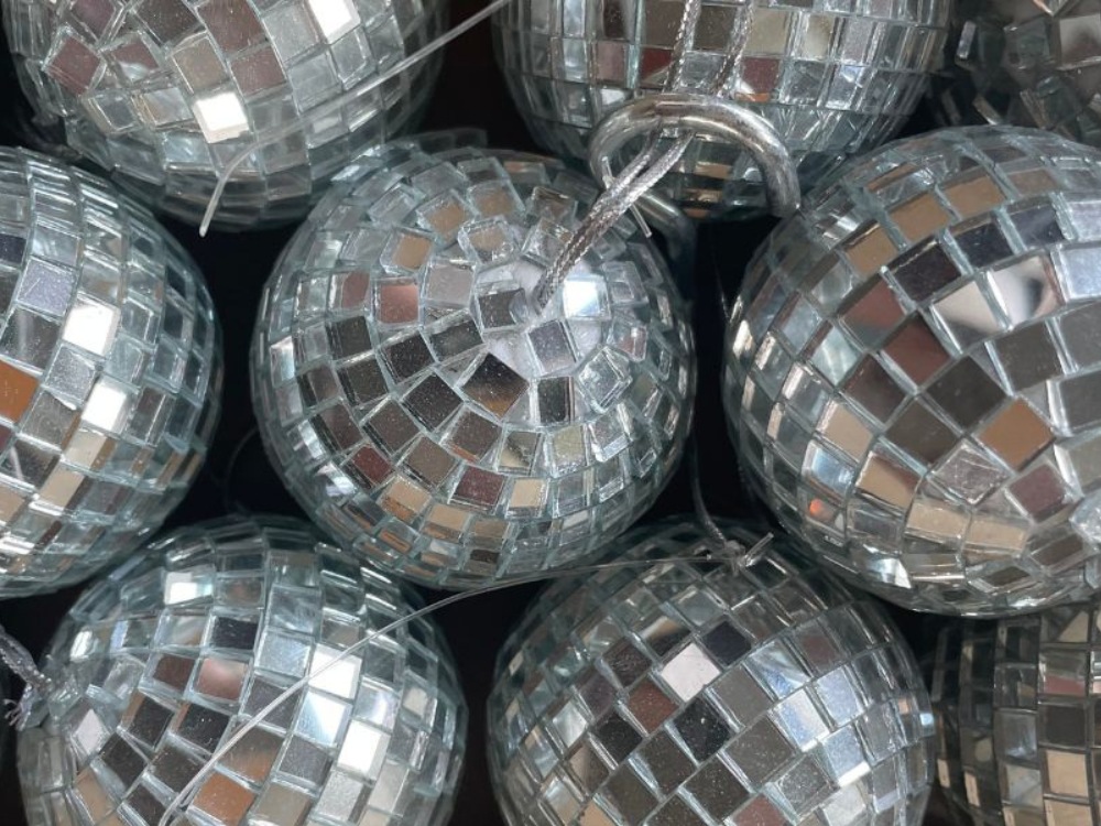A close-up view of sparkling silver disco balls with tiny mirrors reflecting light, creating a festive and vibrant atmosphere.