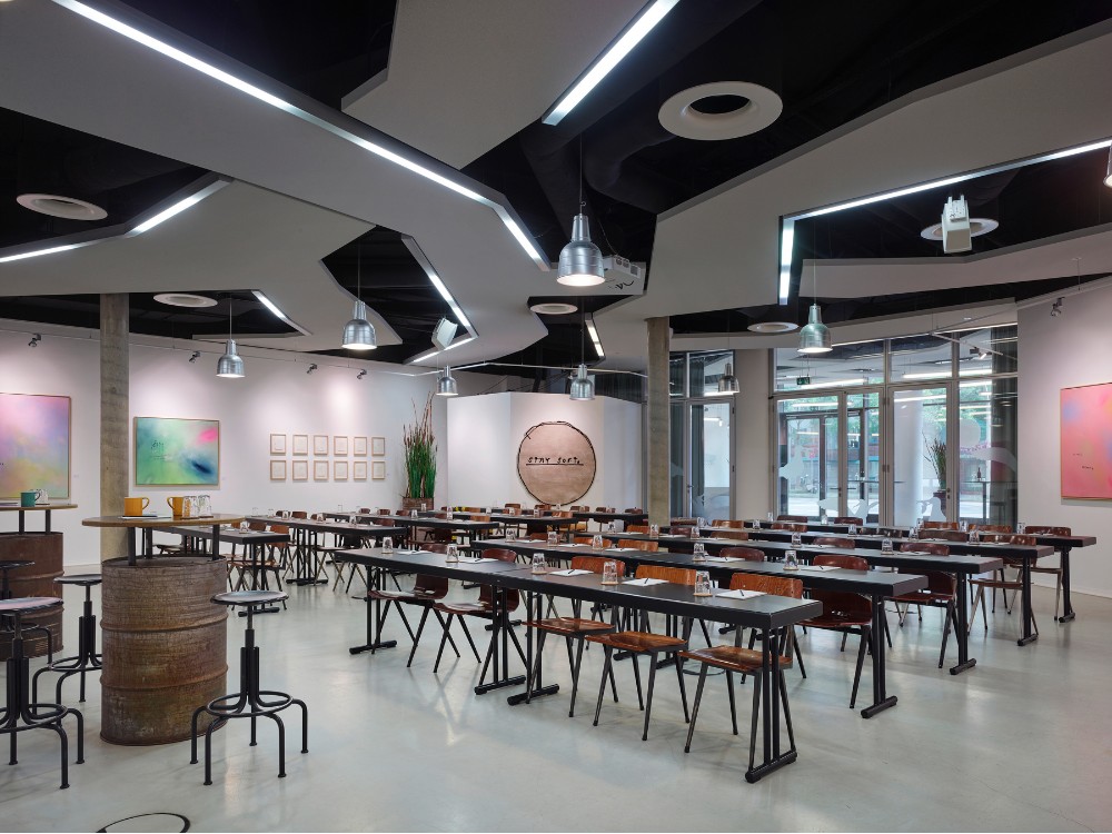 Modern meeting space with sleek tables, artistic wall decor, and ambient lighting, creating a vibrant atmosphere for gatherings.