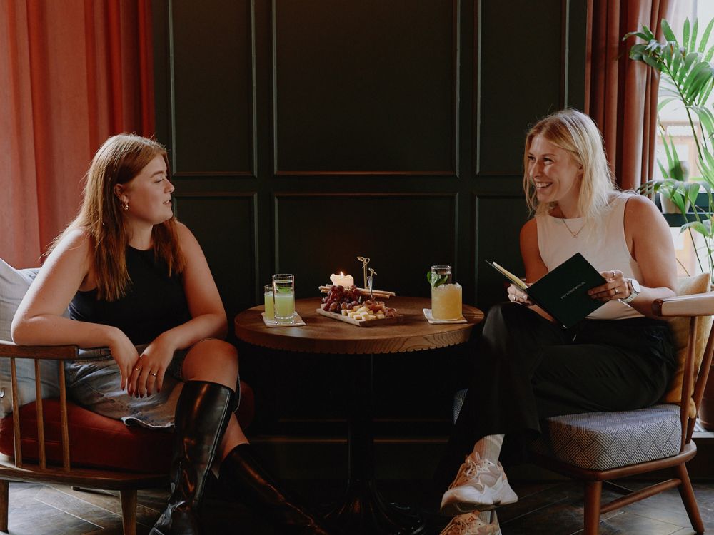 A festive dinner setup inside Rendezvous bar at 25hours Hotel Indre By in Copenhagen. Guests enjoy a cozy candlelit atmosphere with elegant table settings, warm lighting, and celebratory end-of-year vibes.