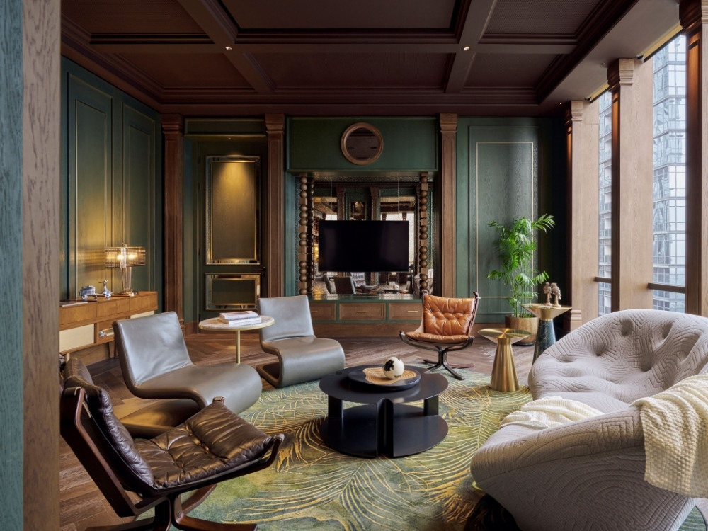 Luxurious living room with modern chairs, a curved sofa, green walls, large windows, and a central black round coffee table on patterned rug.