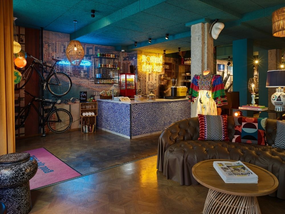 Stylish café interior featuring a patterned bar, bicycles on the wall, colorful art, and cozy seating with vibrant decor elements.