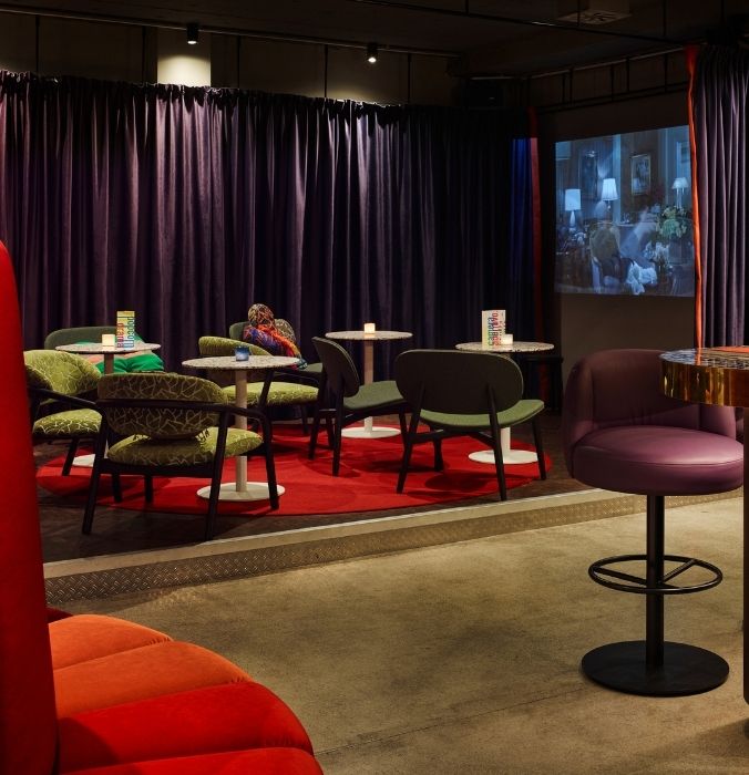 A cosy room filled with bright, colorful chairs and a cinema screen, perfect for relaxation and entertainment.
