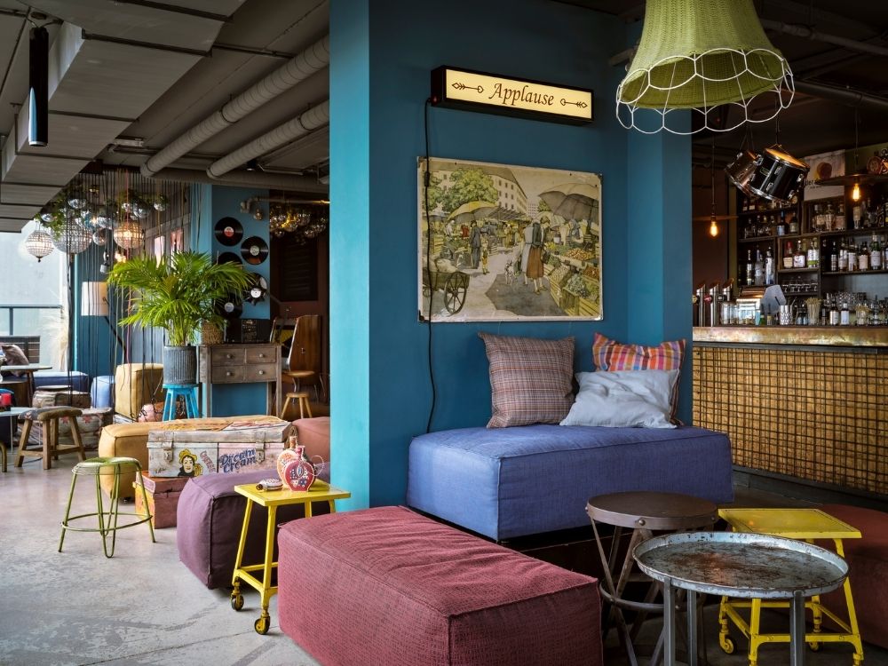 A vibrant bar featuring colorful furniture and a striking painting on the wall, creating a lively atmosphere.
