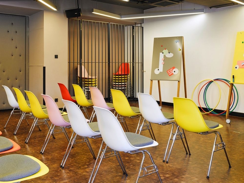 A meeting room featuring several chairs arranged around a presentation board displaying a slide.