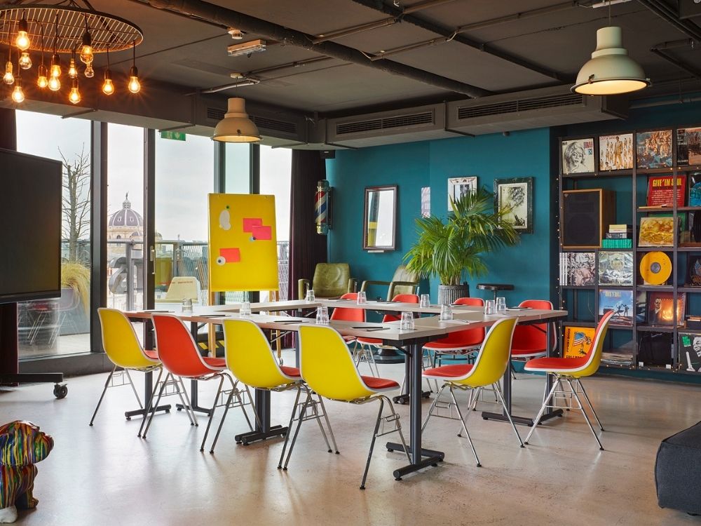 A modern conference room showcasing an array of colorful chairs and tables for collaborative work.