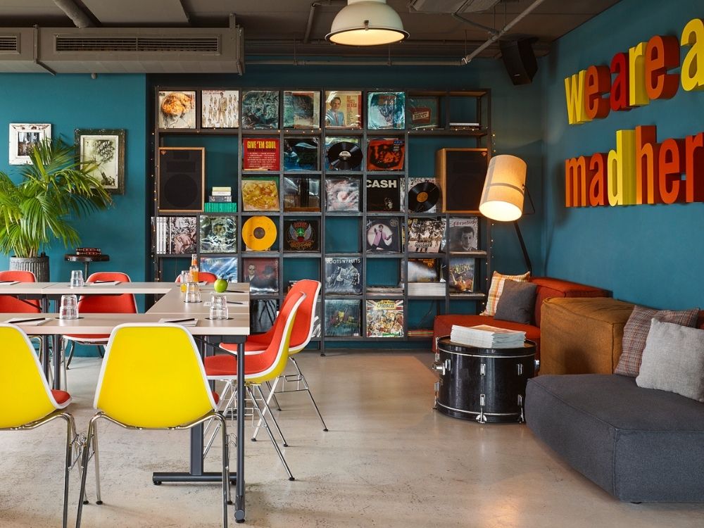 A vibrant room featuring colorful chairs and tables, with a wall-mounted record player as a focal point.