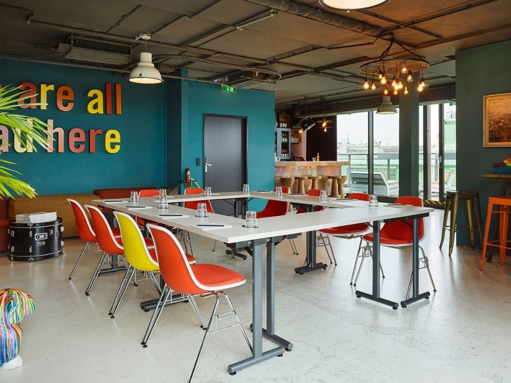 A conference room featuring vibrant chairs and tables arranged for a meeting setting.