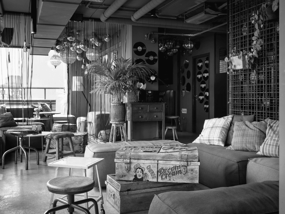 A black and white photo of a cosy bar featuring a sofa, coffee table, and decorative elements.