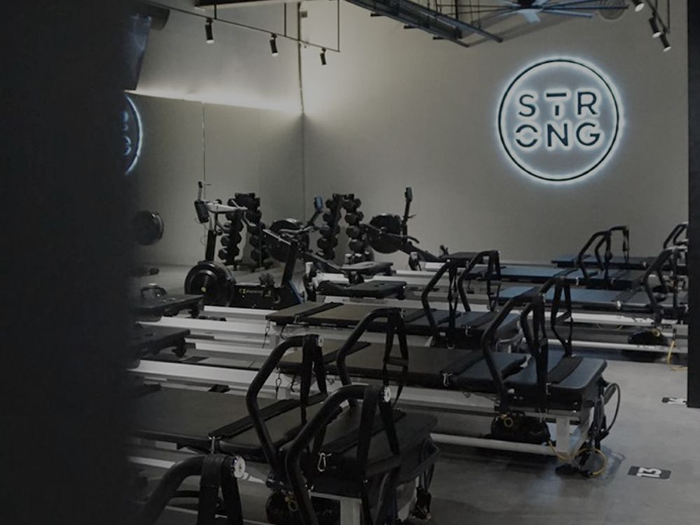 A pilates studio interior featuring a prominent sign that reads "Strong," emphasizing strength and fitness.